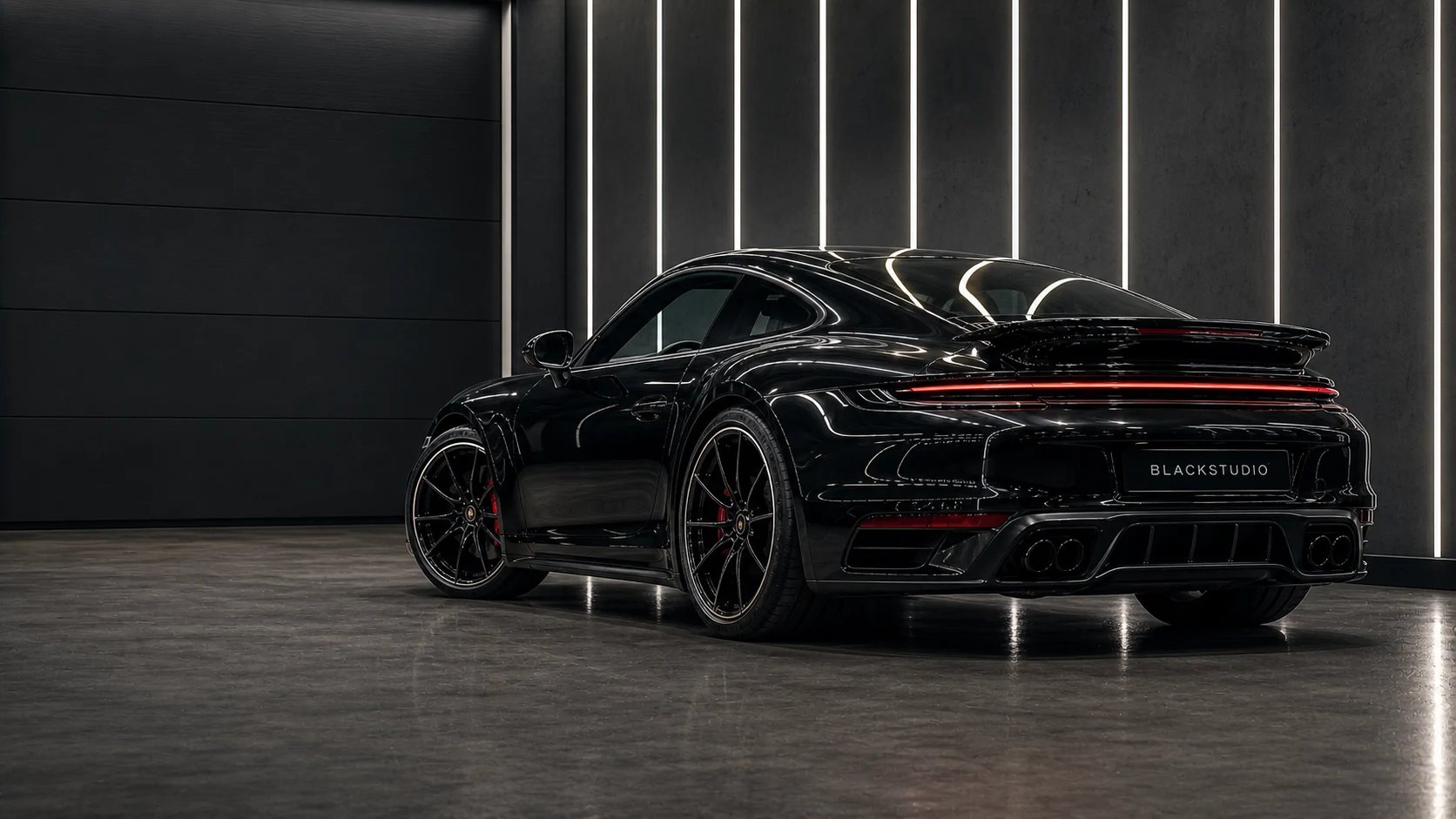 Чёрный Porsche 911 с номером BLACKSTUDIO в графитовой студии